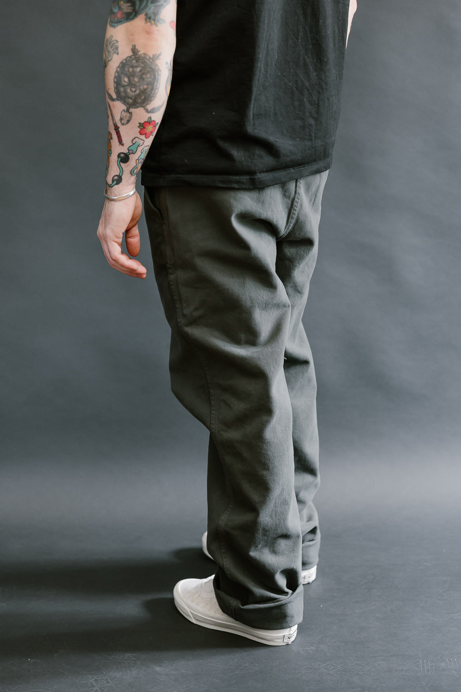 Person wearing dark pants and a black shirt against a gray background