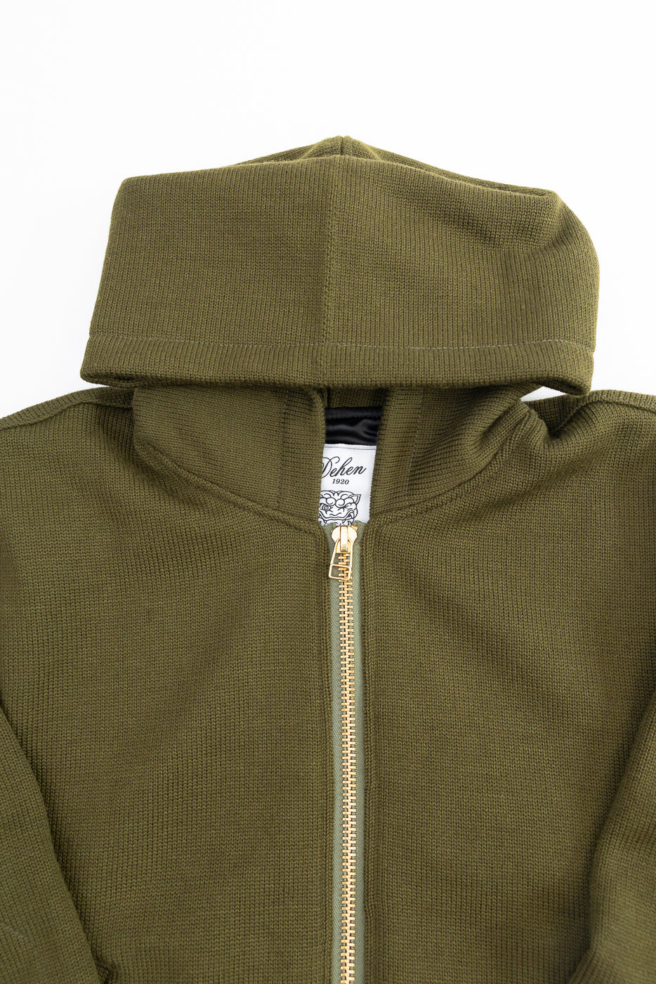 close up of brass zipper and hood on knitted olive green zip up hoodie