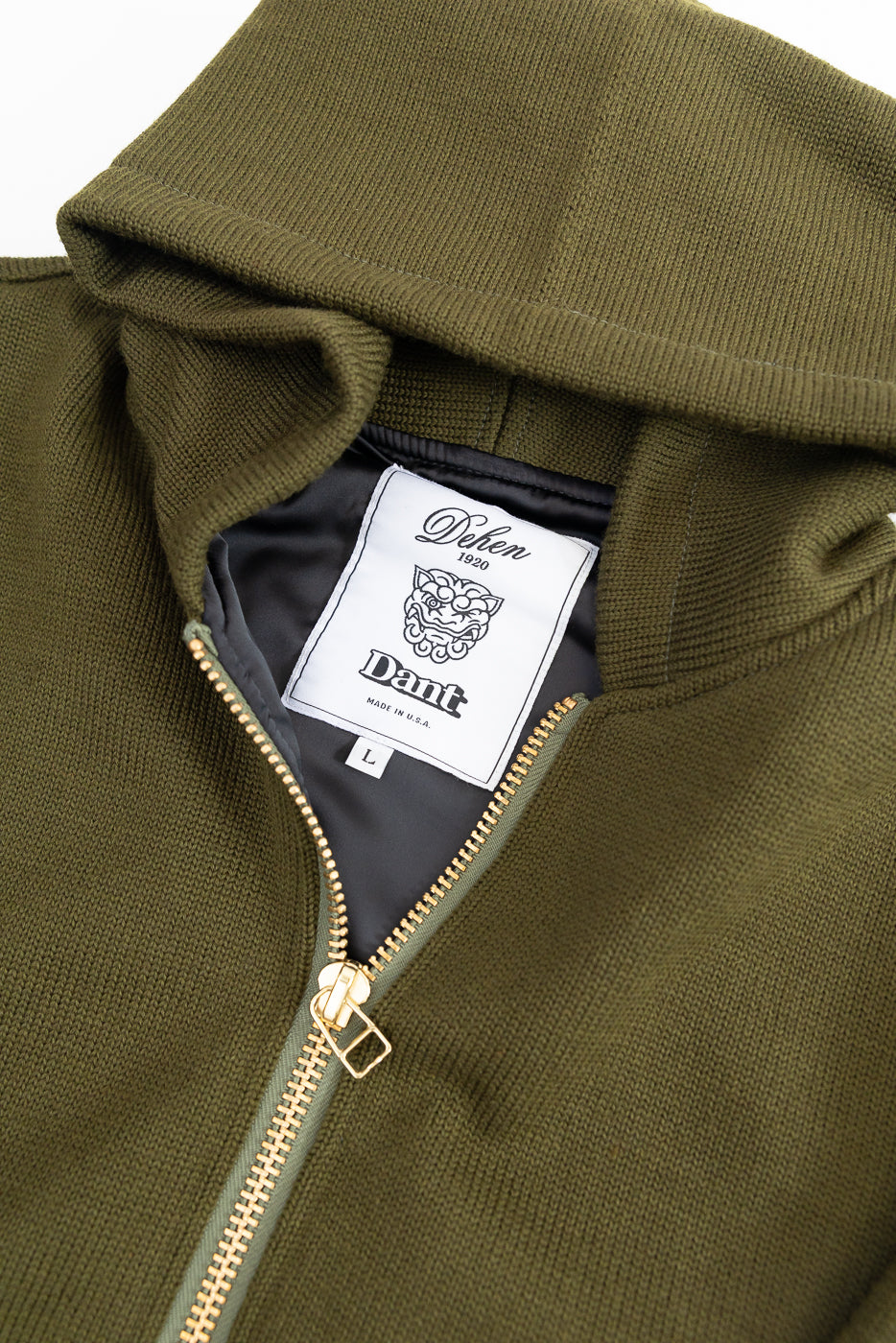 close up of white and black dehen x dant tag on interior of olive green knitted hoodie