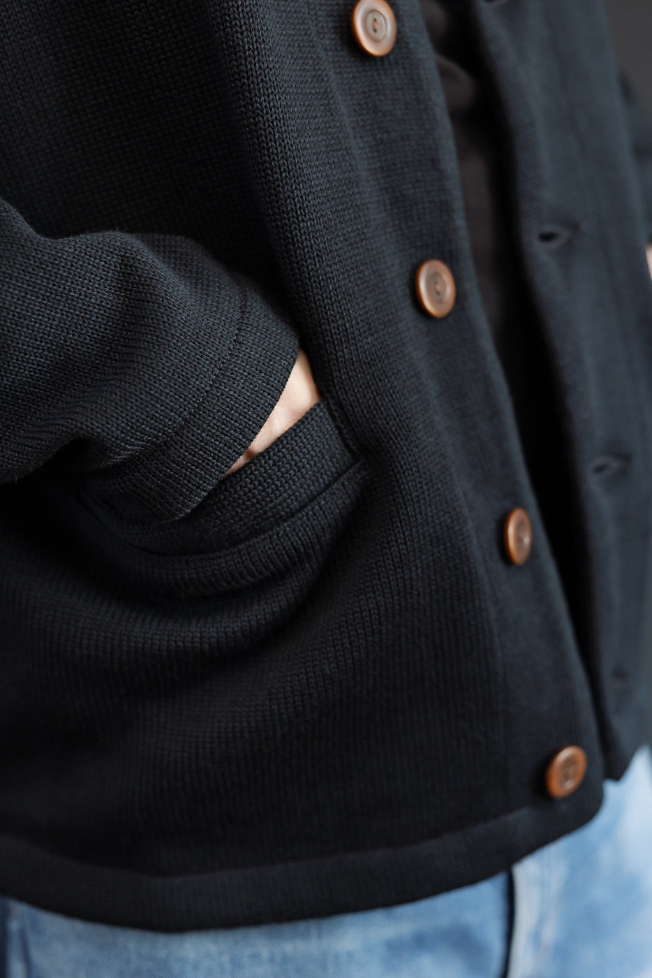close up of open hand in pocket of black cardigan
