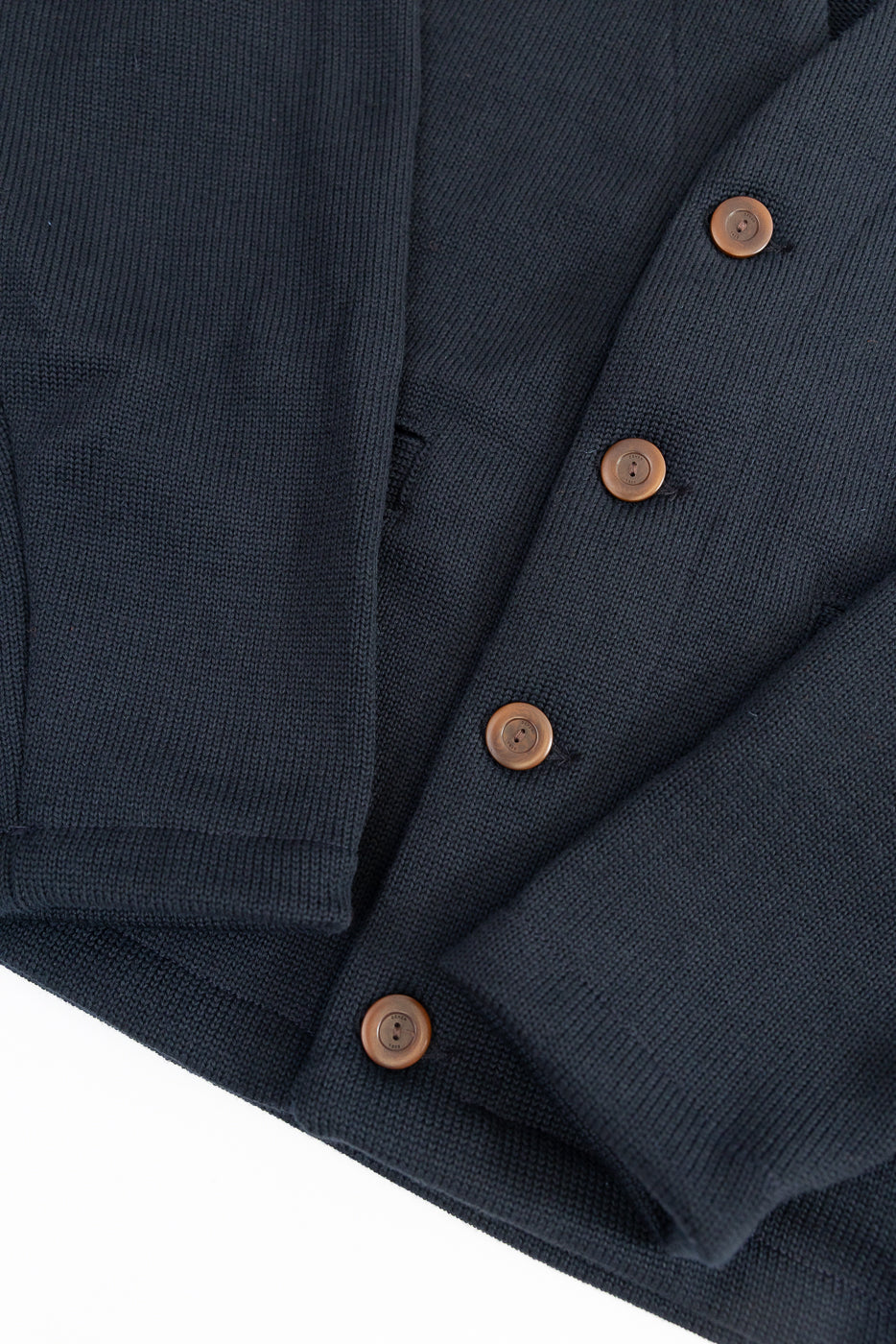 Black Dant slouchy cardigan with brown buttons on a white background, close up on sleeves and button placket