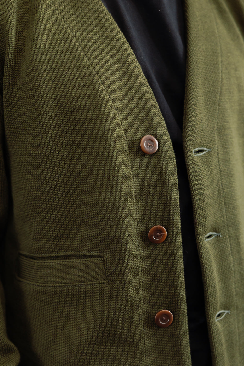 close up of placket of olive green cardigan with brown corozo buttons, black t-shirt underneath