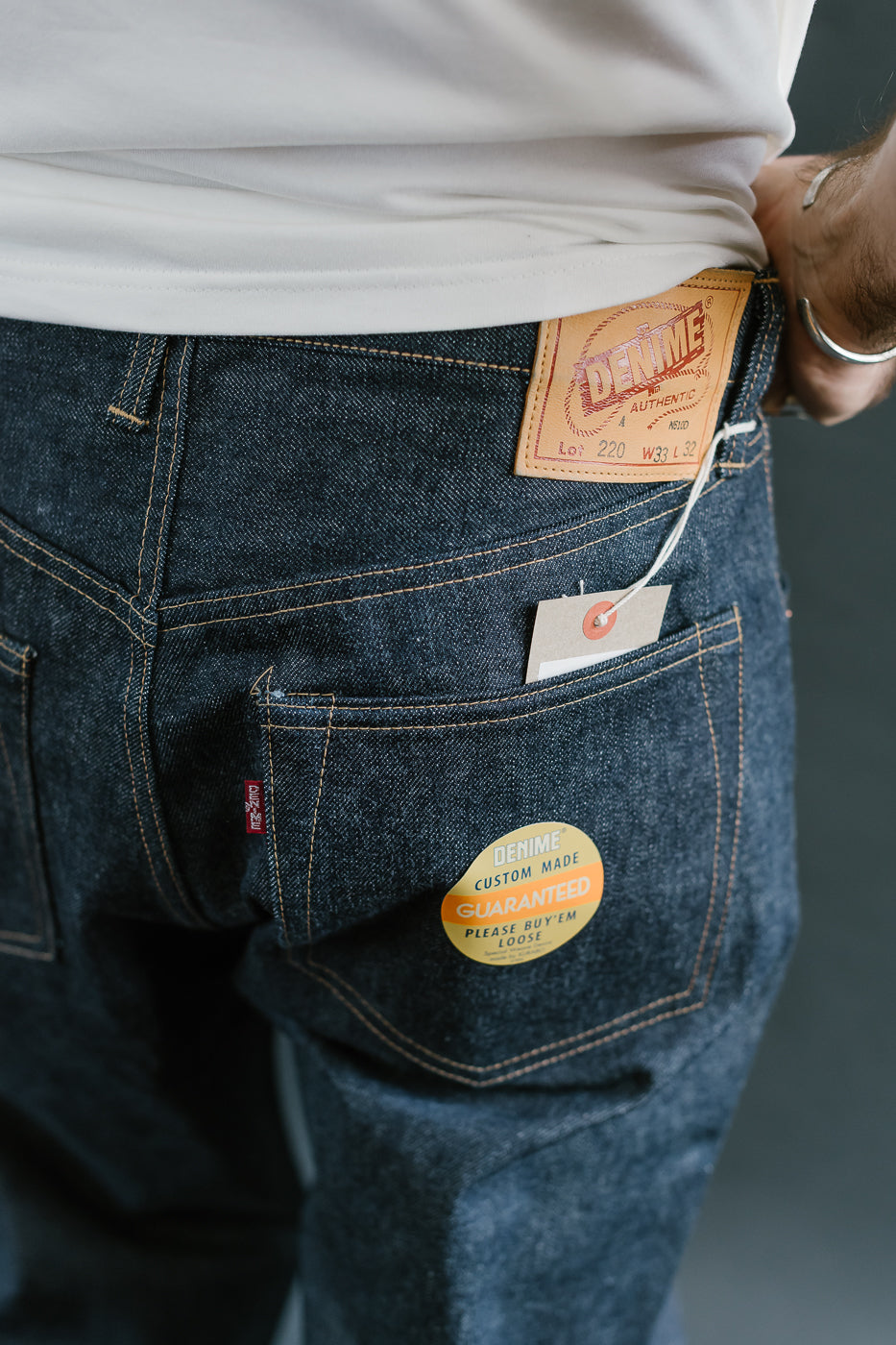 Person wearing blue jeans with Levi's branding and a custom label on the back pocket.
