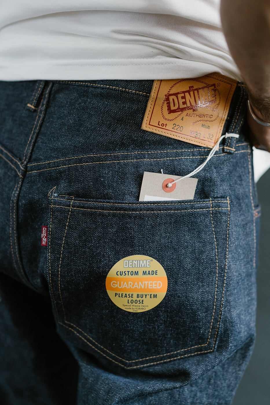 Close-up of a person wearing blue jeans with a Denim brand label and tag.