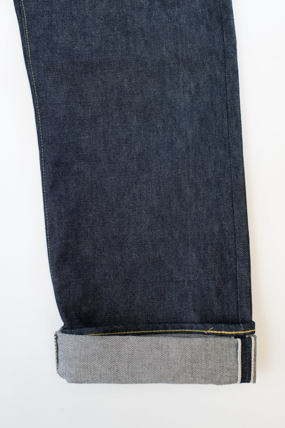 Close-up of dark blue jeans with a white background