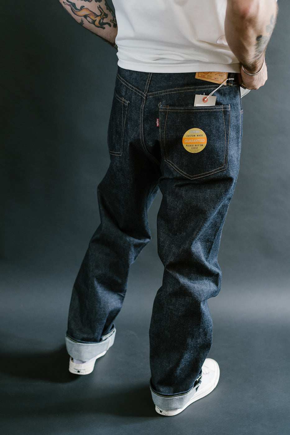 Person wearing dark blue jeans with a Levi's patch on a gray background