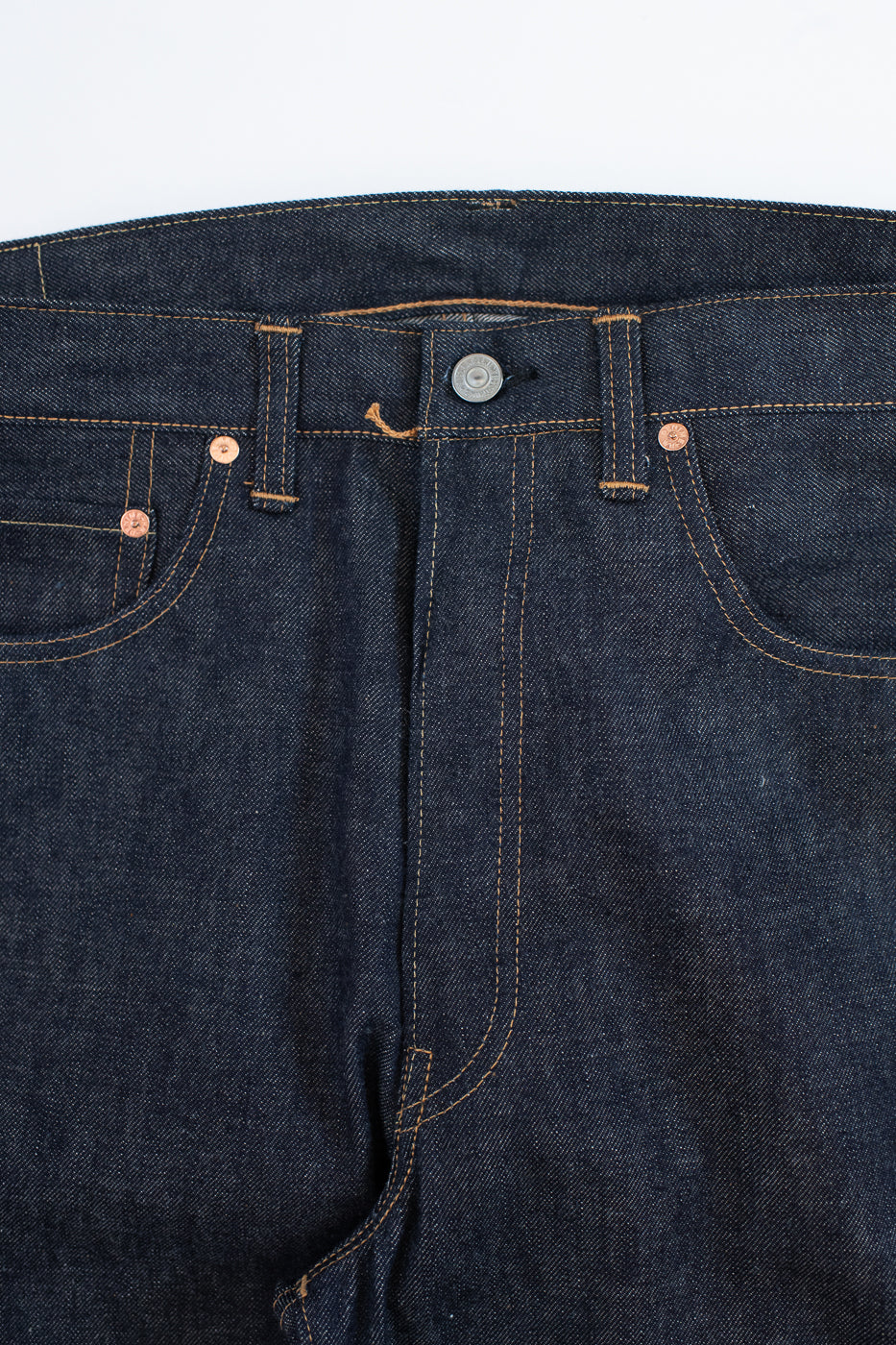 Close-up of dark blue denim jeans on a white background