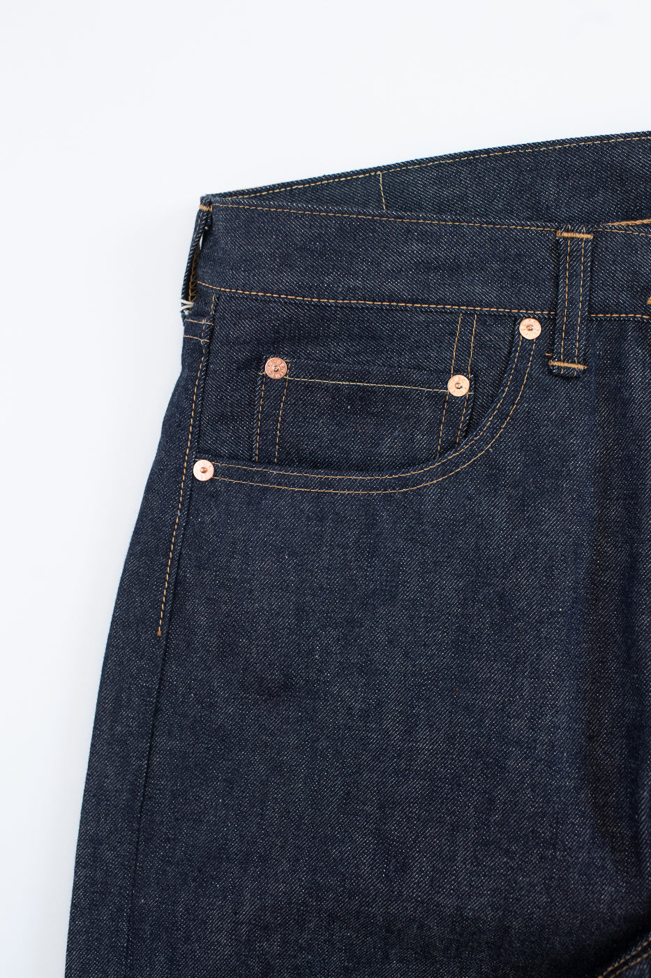 Close-up of dark blue denim jeans with a white background