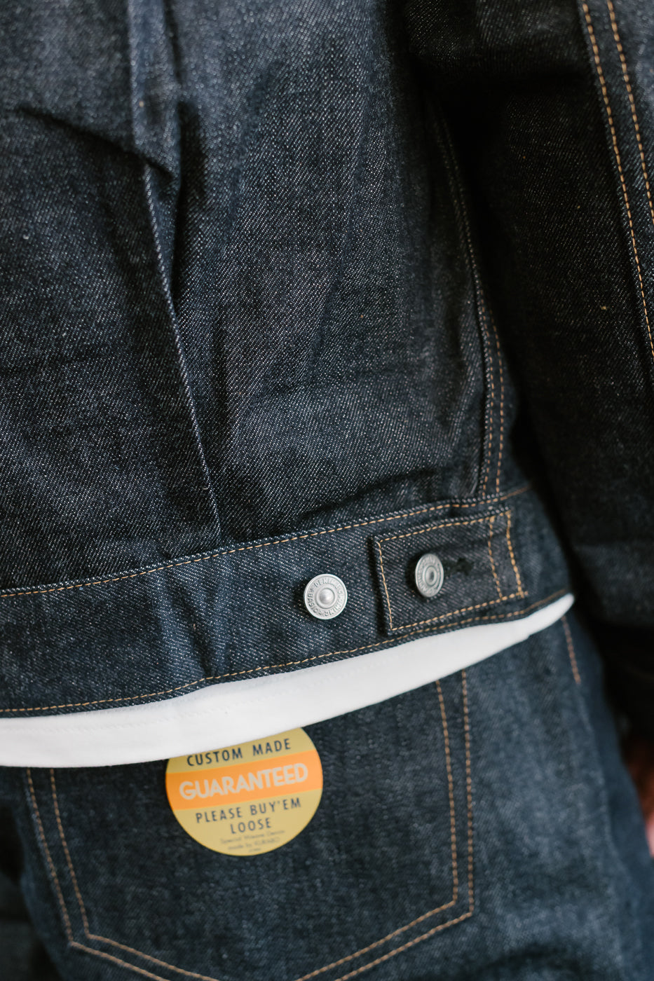 Close-up of a dark denim jacket with a label on the pocket.
