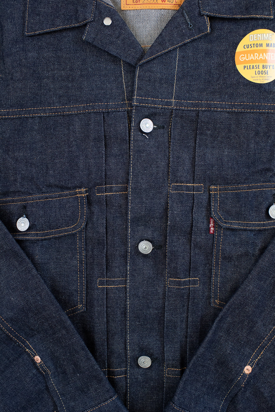 Close-up of a blue denim jacket with buttons and a brand label.
