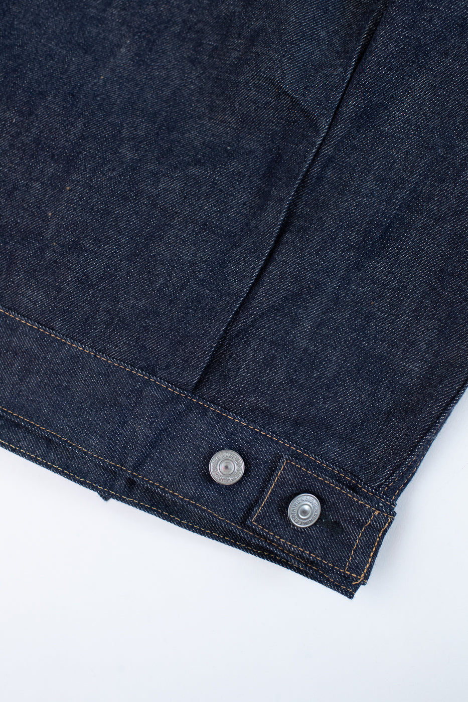 Close-up of a dark blue denim jacket with button details on a white background