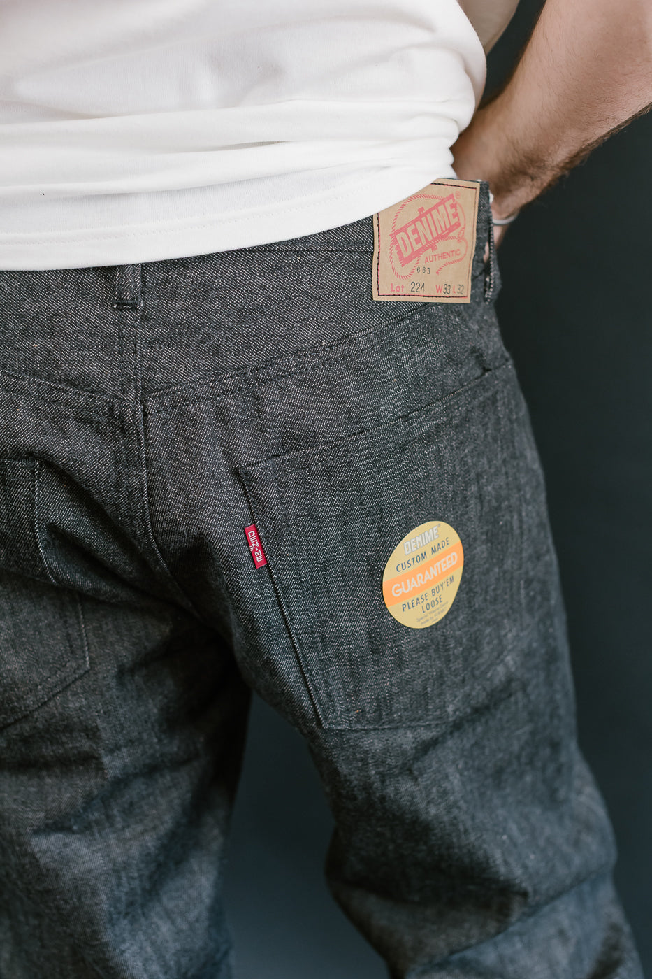 close up of on body denime black x mother cotton back pocket, paper patch, sticker and red tab