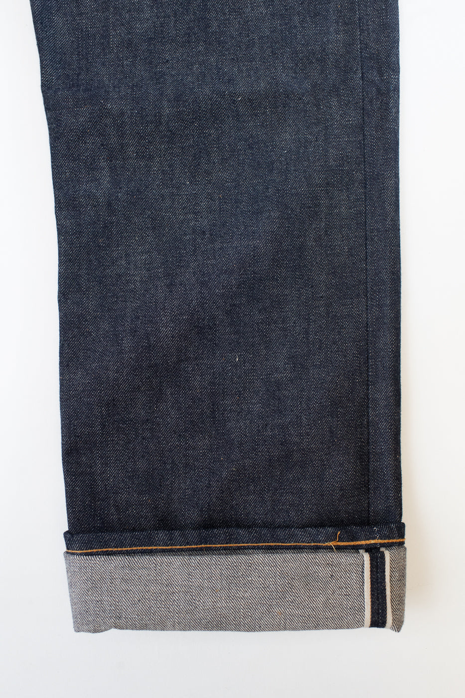 Close-up of dark blue denim jeans with a white background