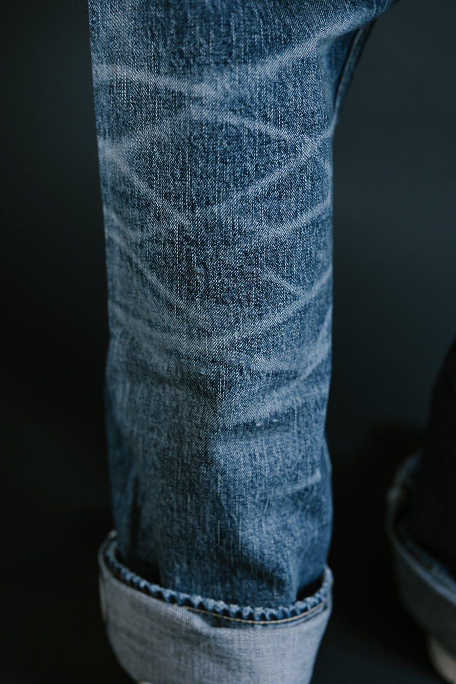 Close up of heavily washed denim jeans honeycomb on back of legs and top of roping on cuff.