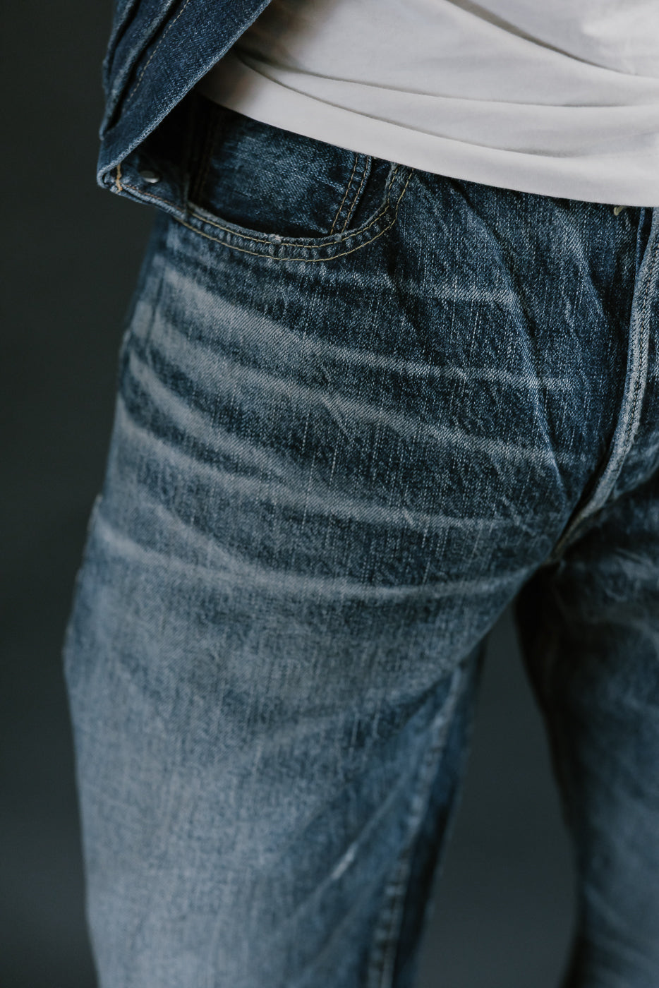Close up of heavily washed denim jeans whiskers and coin pocket.