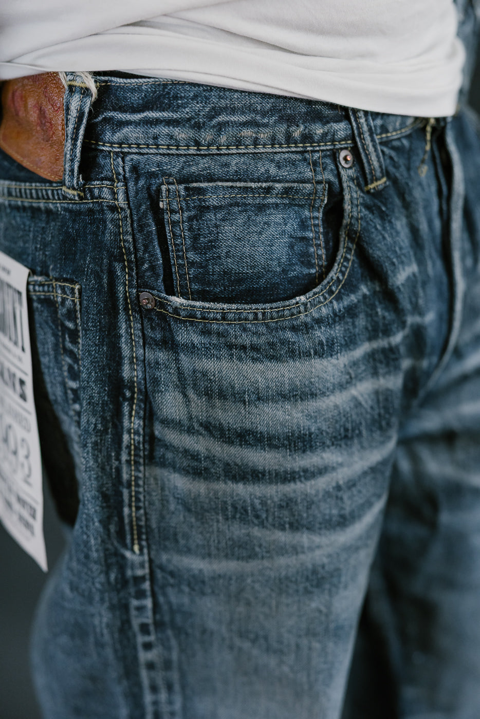 Close up of heavily washed denim jeans whiskers and coin pocket.