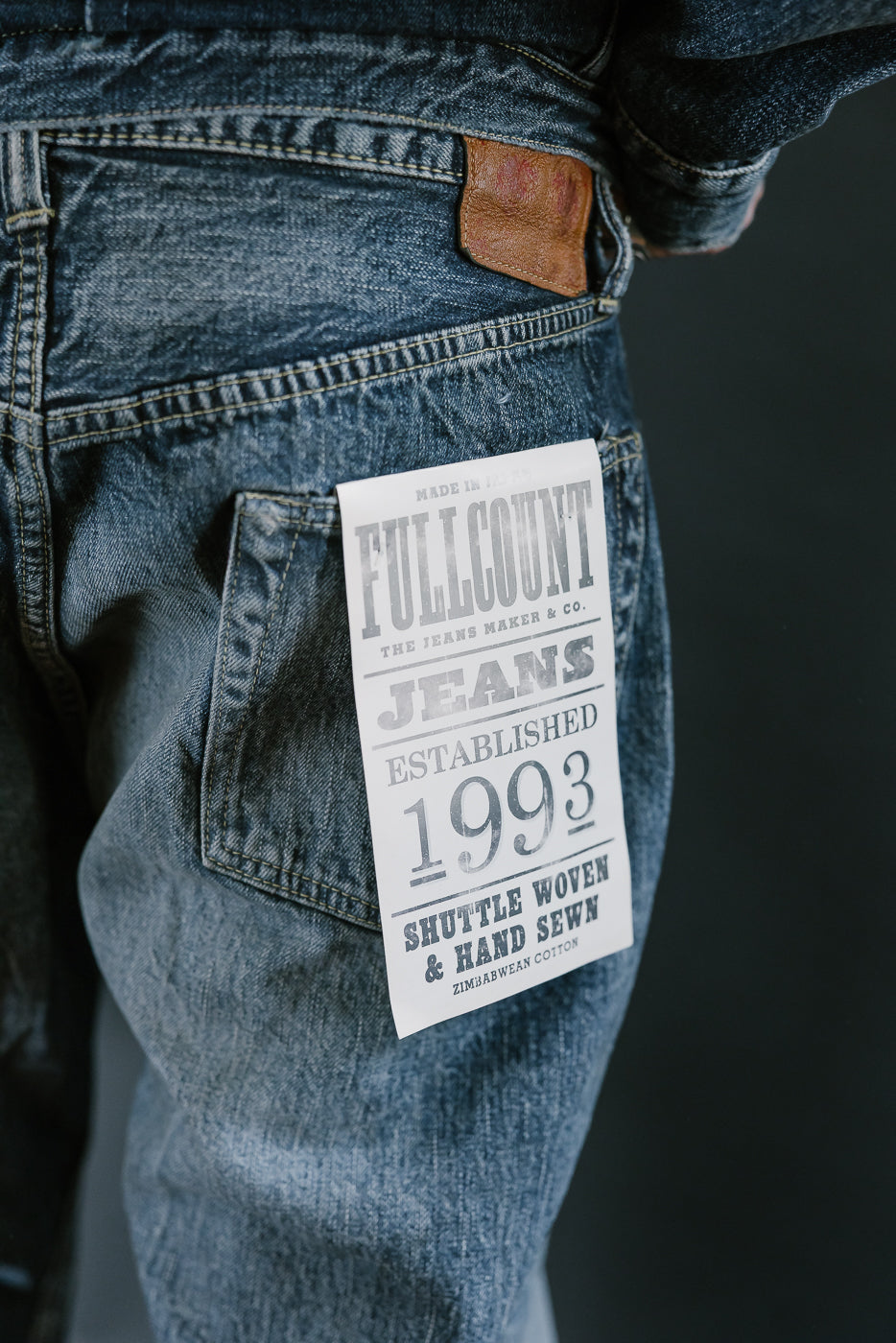 Close up of heavily washed denim jeans back pocket with white flasher and leather tag.