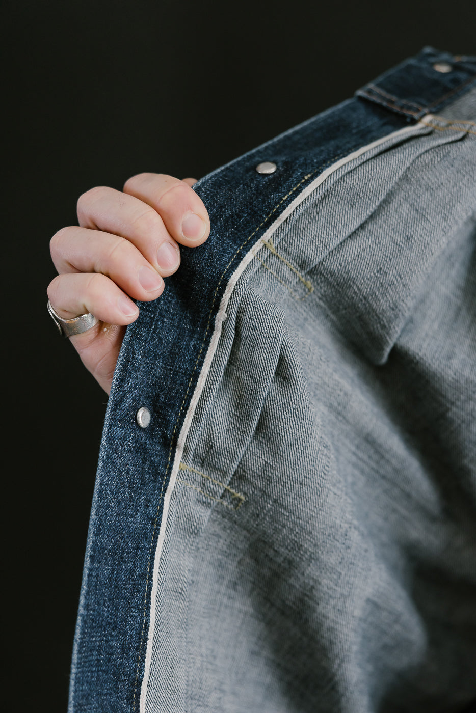 Bearded man wearing Heavily washed indigo denim jacket. Interior shot of selvedge ticker.