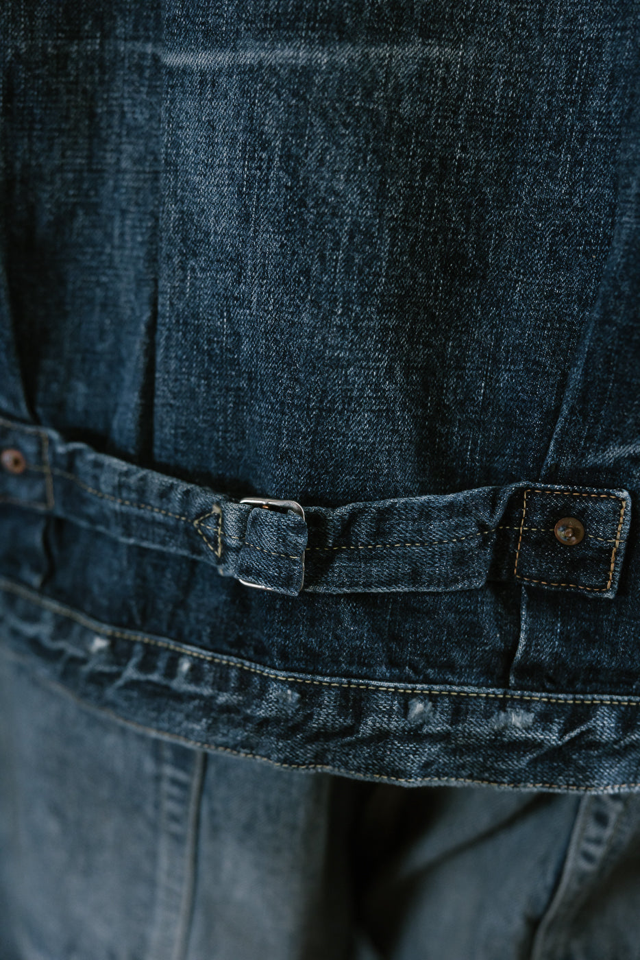 Bearded man wearing Heavily washed indigo denim jacket. Close up of cinch back.