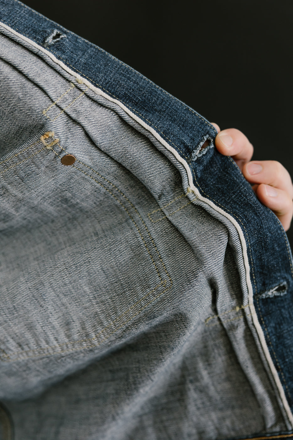 Bearded man wearing Heavily washed indigo denim jacket. Close up of other side of selvedge placket.