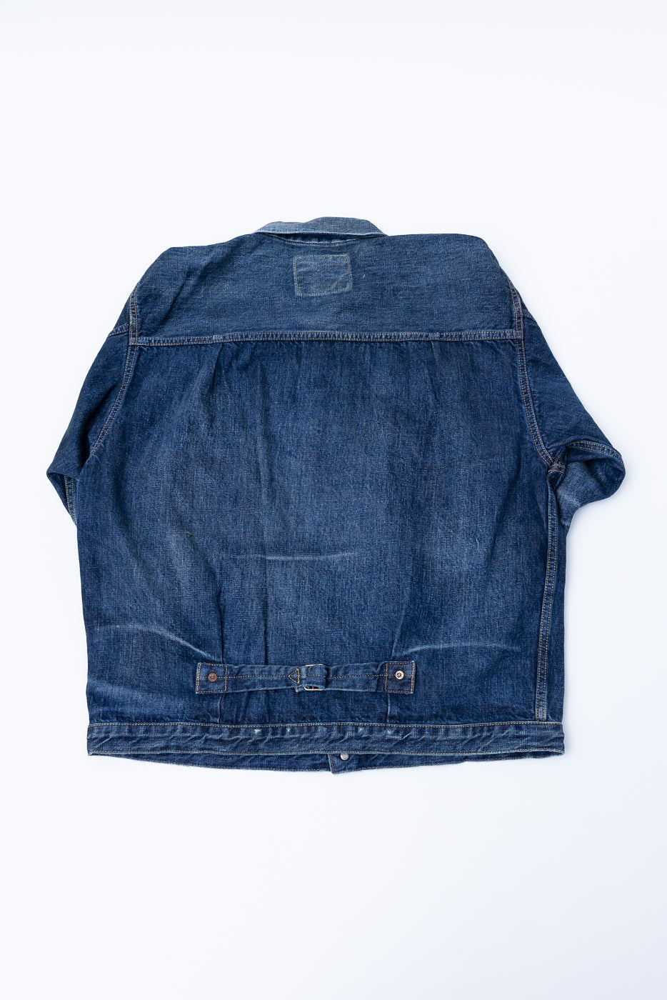 Heavily washed indigo denim jacket with a visible full count label on the left chest pocket on a white background, full lay flat, back side.