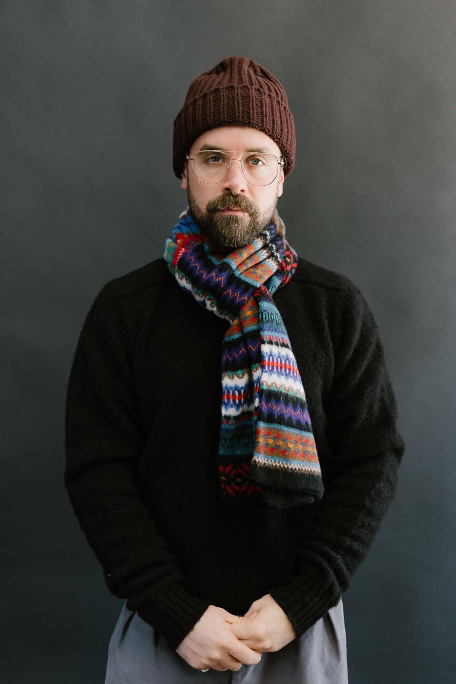 multicolored, patterned wool scarf with a black base on bearded man with a black sweater, front view