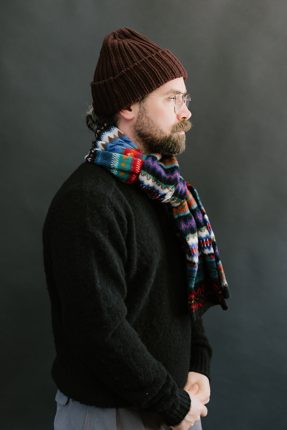 multicolored, patterned wool scarf with a black base on bearded man with a black sweater, side view