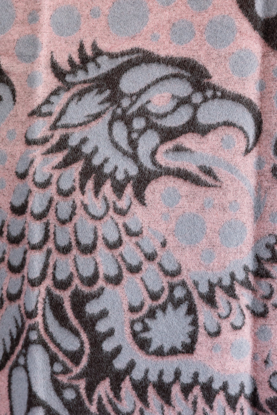 close up of pink blanket with grypon head, wings, and bubble pattern, front