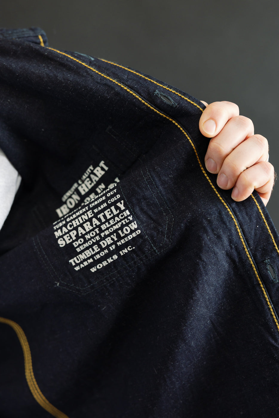Close-up of inside pocket and care tag on indigo work shirtshowing interior stitching detail.