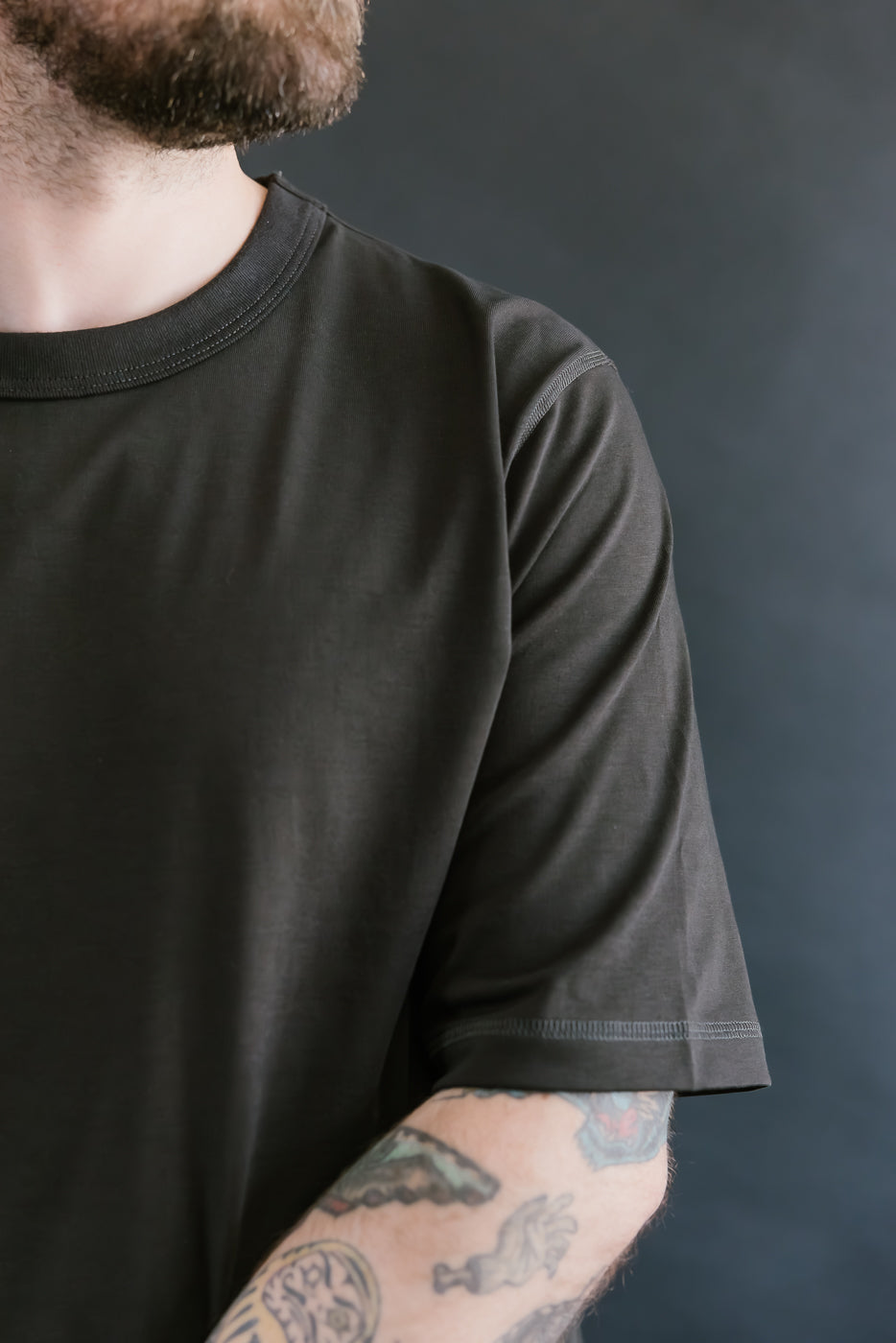 Person wearing a black t-shirt with a dark background