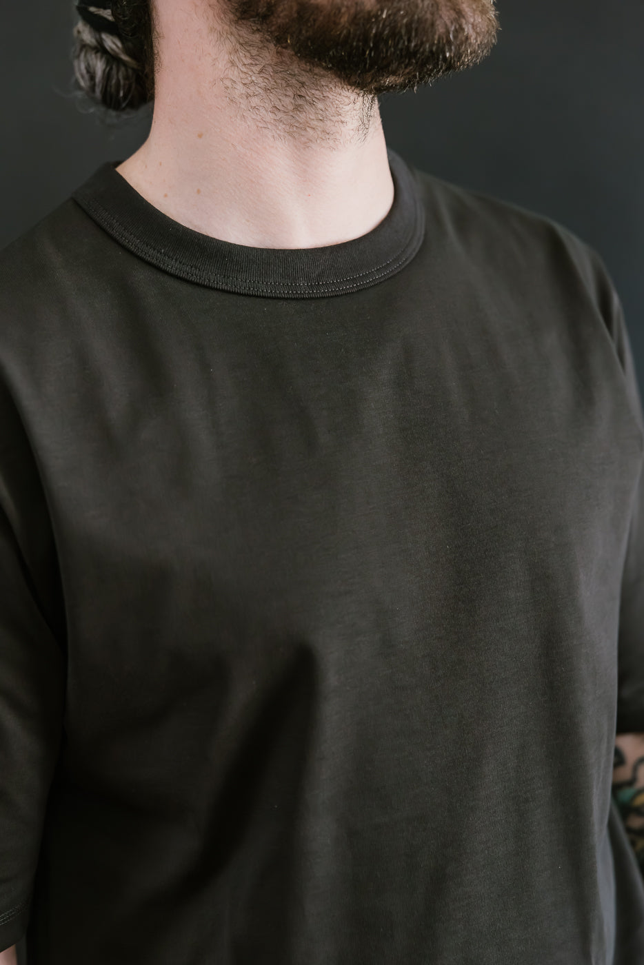 Person wearing a black long-sleeve shirt against a dark background