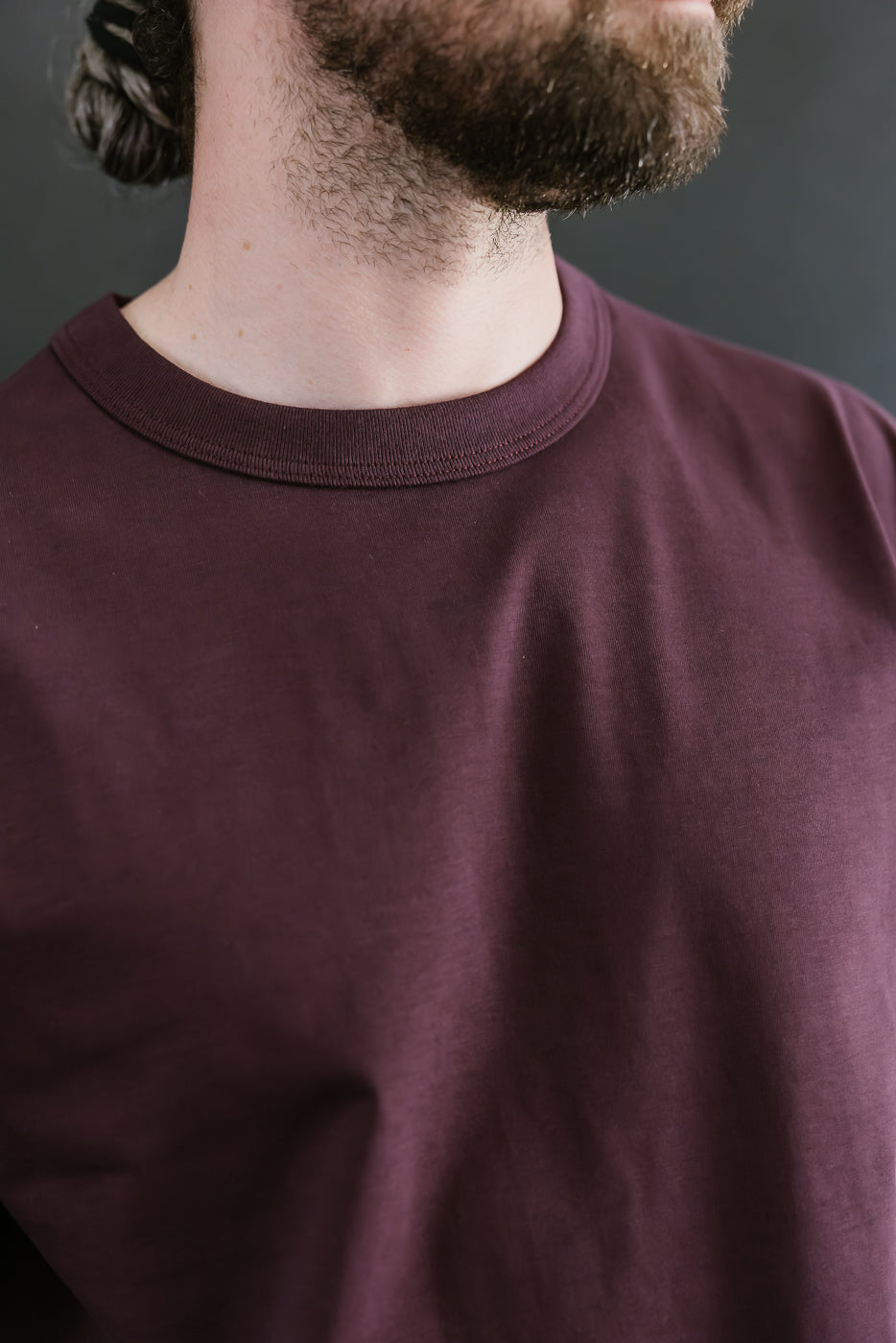 Person wearing a maroon shirt with a neutral background