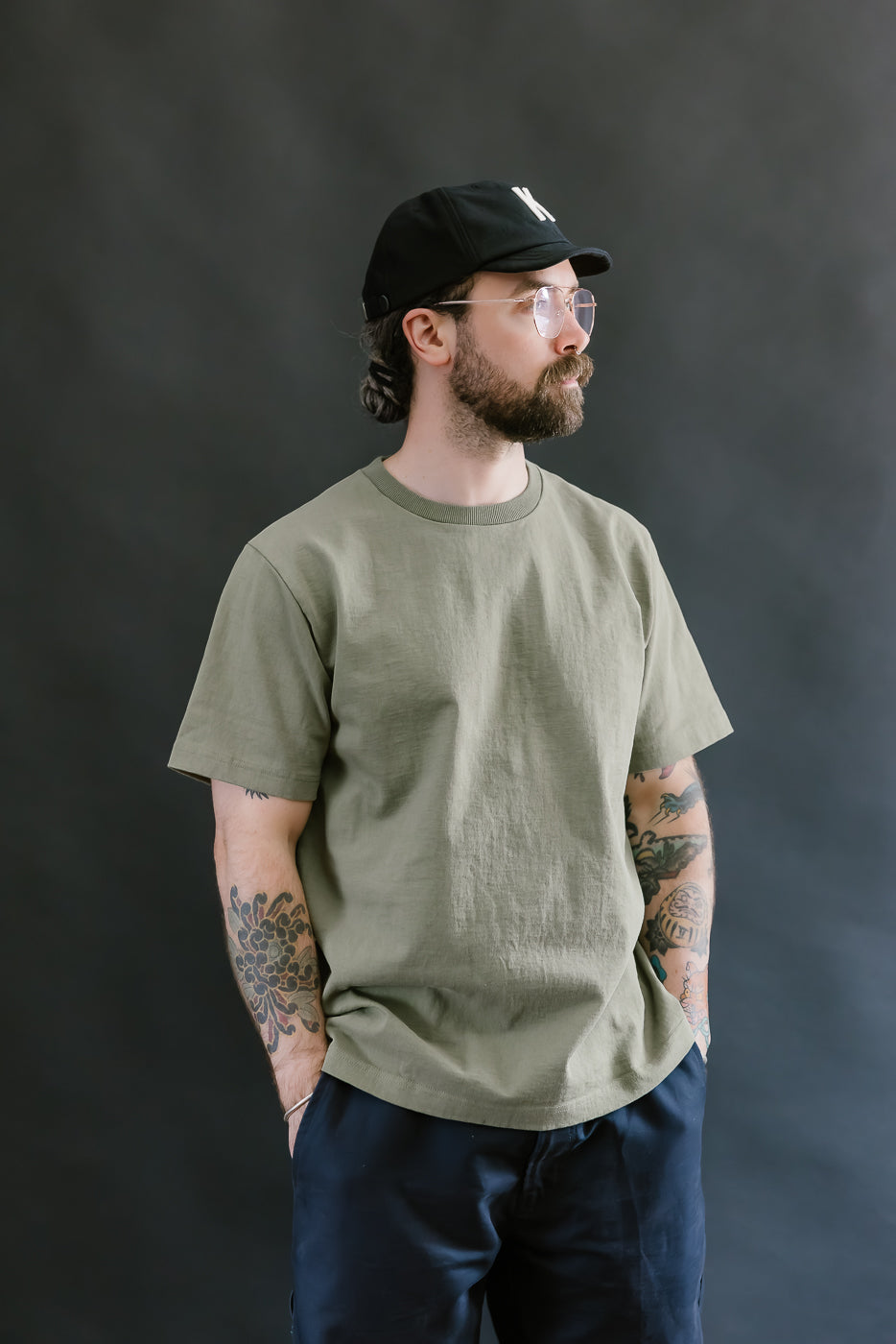 Man wearing a green t-shirt and black cap against a dark background