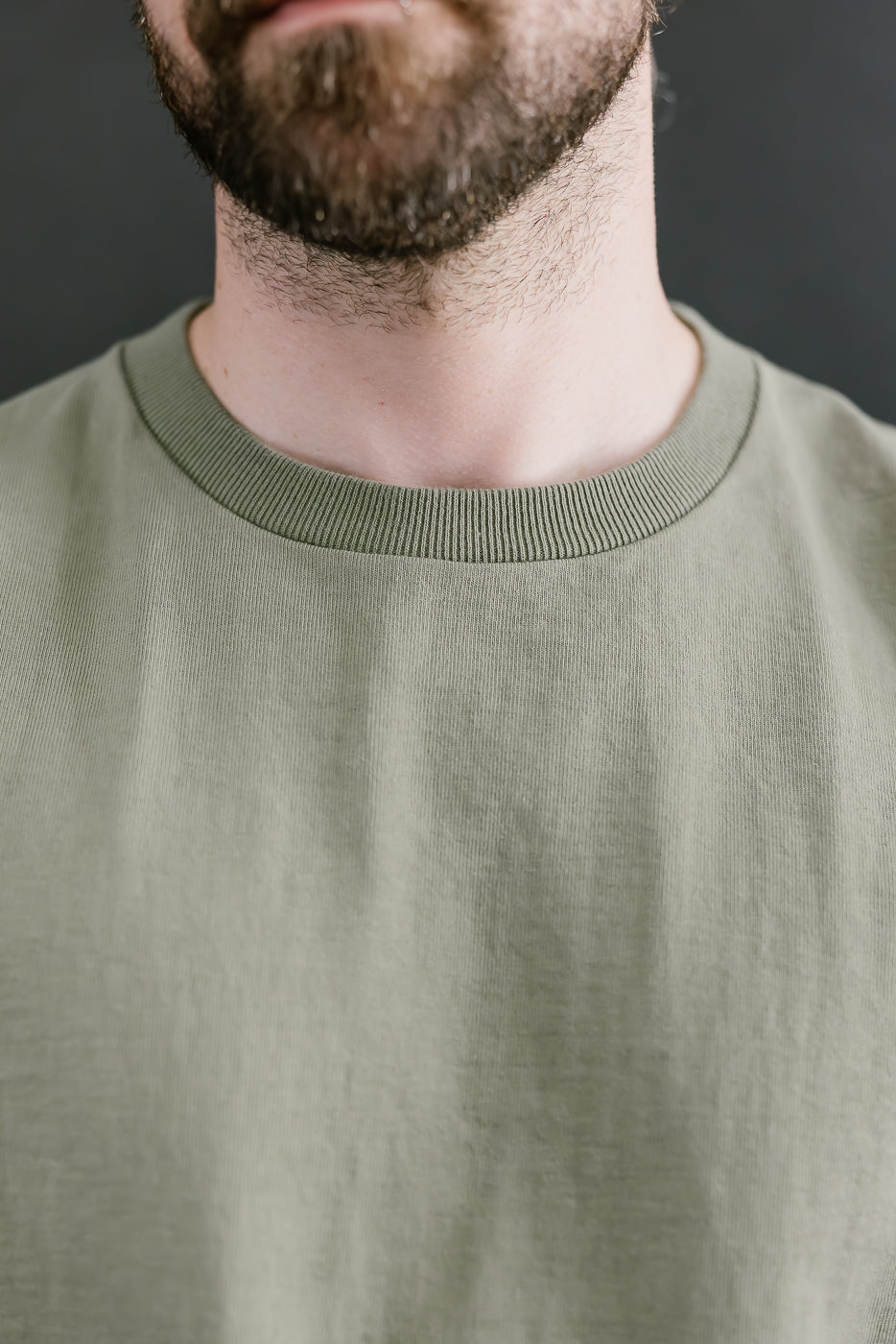 Person wearing a green sweater against a dark background