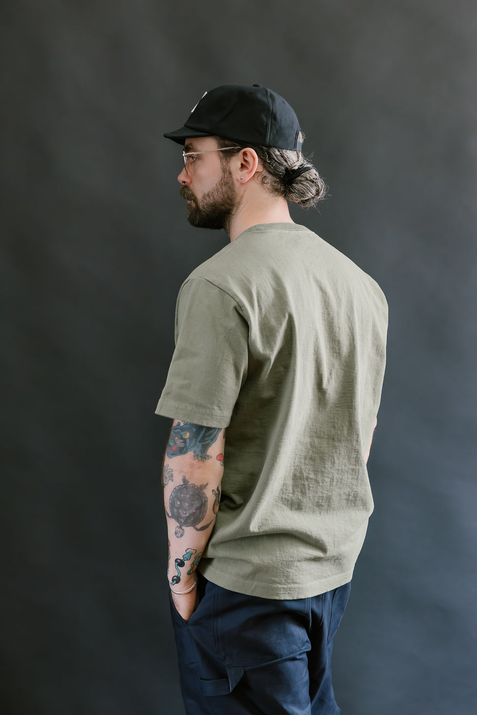 Man wearing a green t-shirt and black cap against a dark background