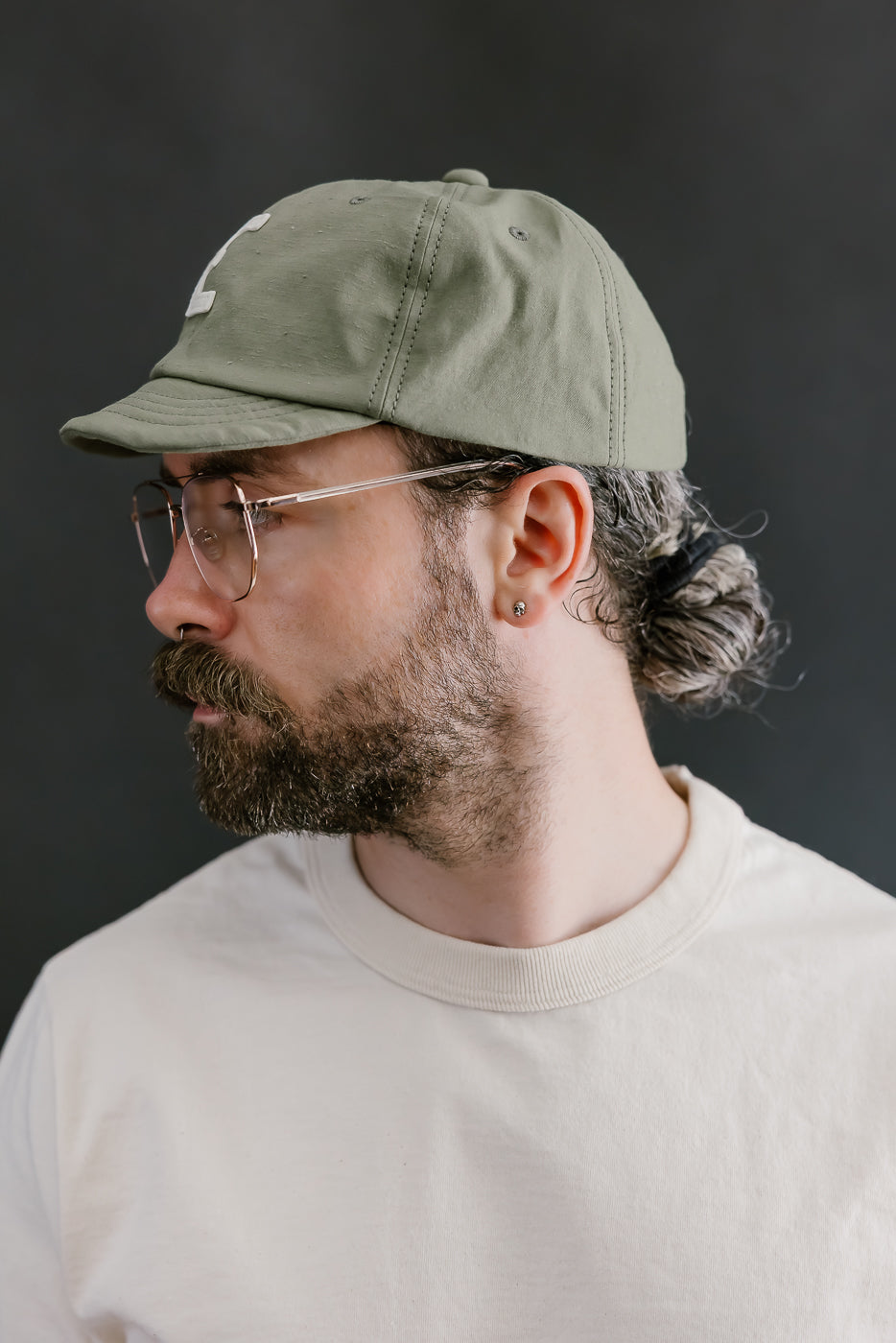 Man wearing a green cap and glasses against a dark background