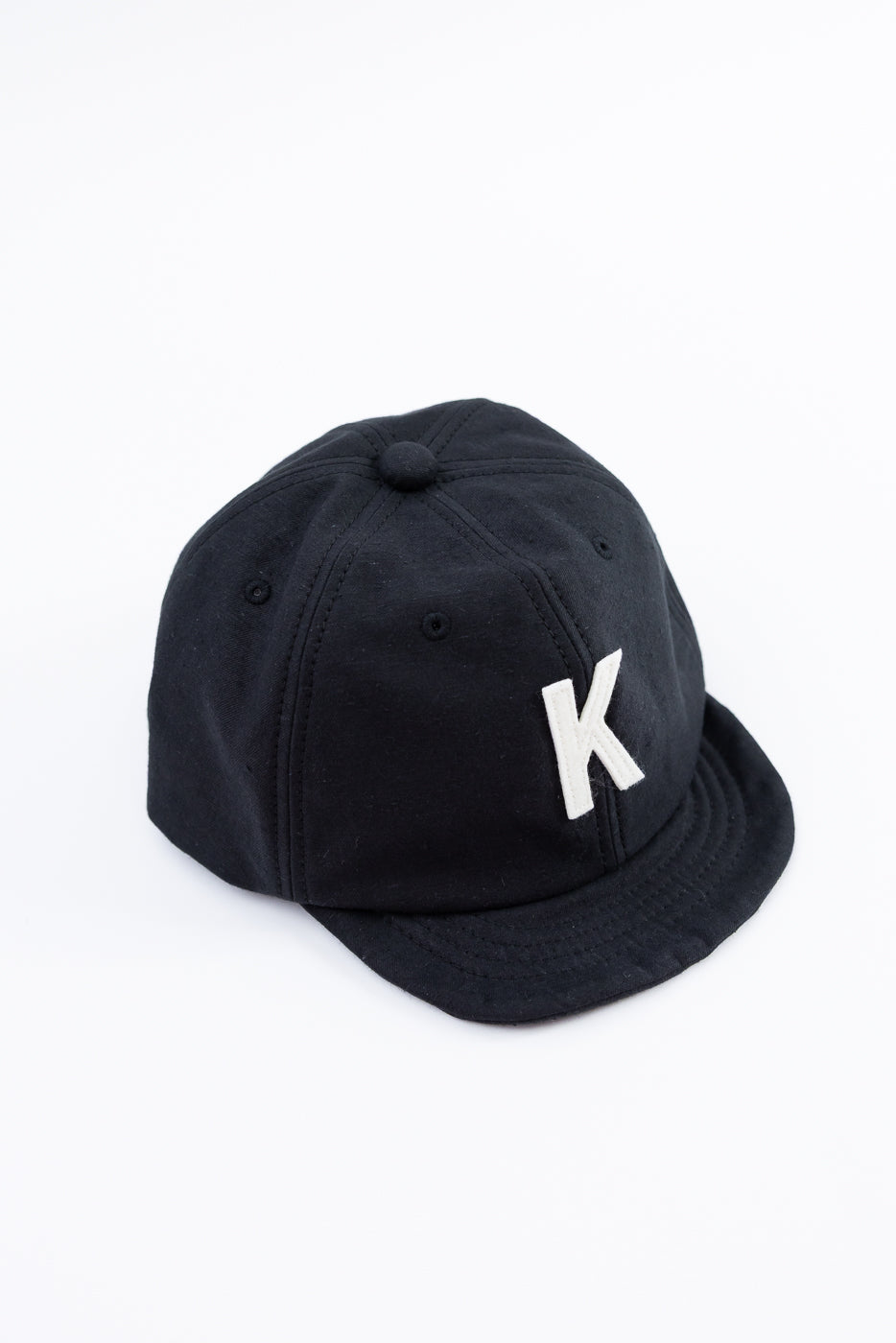 Black cap with a white 'K' logo on a white background