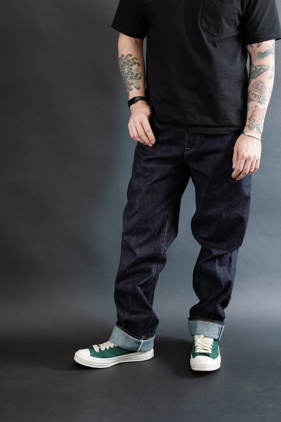 3/4 view, Man wearing a black t-shirt, dark RGT 15oz rinsed selvedge jeans, green shoes, front view