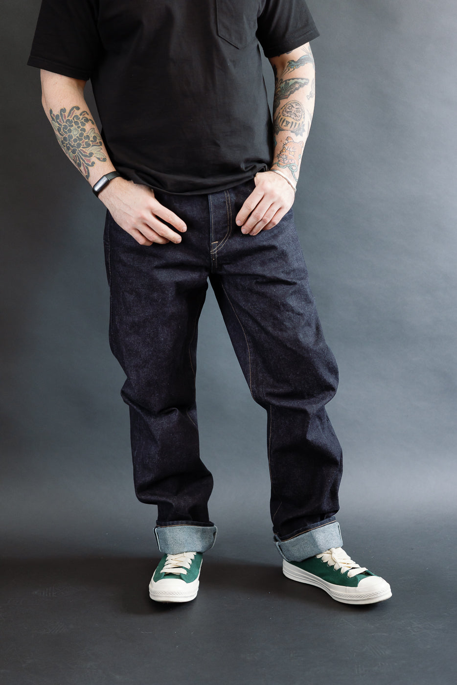 3/4 view, Man wearing a black t-shirt, dark RGT 15oz rinsed selvedge jeans, green shoes, front view