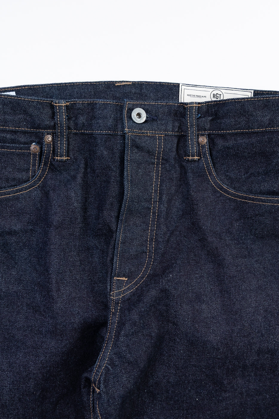 Close-up of dark blue jeans with a visible brand label on a white background
