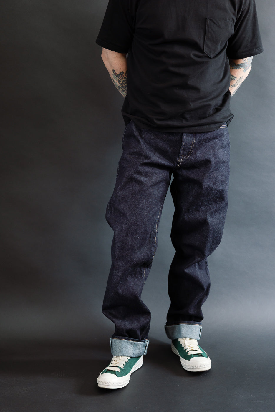 3/4 view, Man wearing a black t-shirt, dark RGT 15oz rinsed selvedge jeans, green shoes, front view