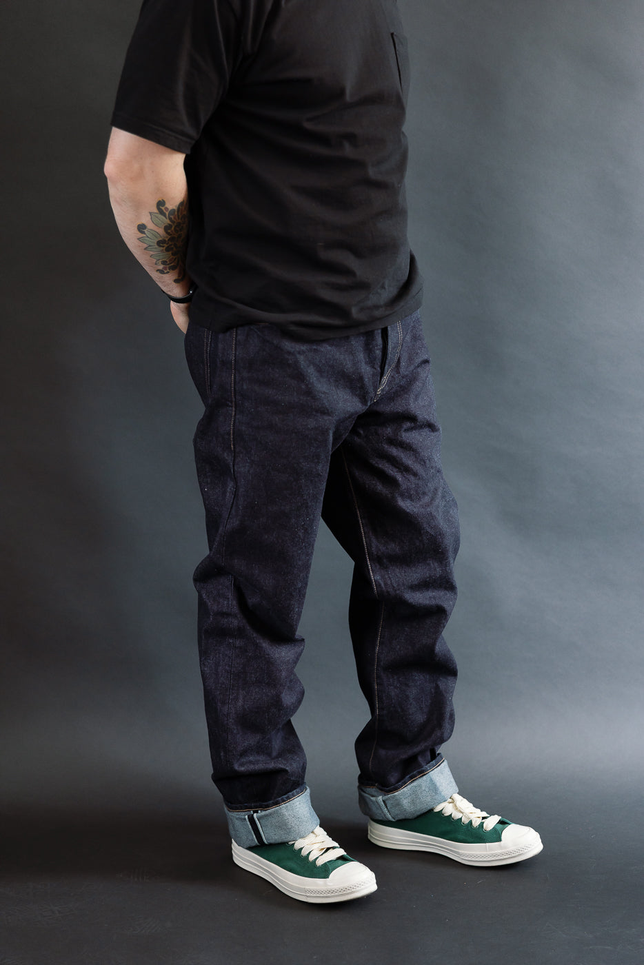 3/4 view, Man wearing a black t-shirt, dark RGT 15oz rinsed selvedge jeans, green shoes, side view