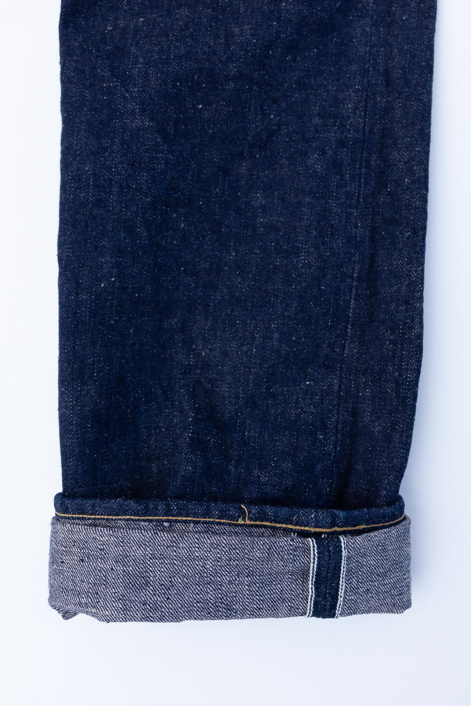 Close-up of Samurai S500AX-SAKURA jeans cuffed to reveal selvedge edge, showcasing 18oz AI-PLUS denim with sakura-dyed weft and natural indigo warp.