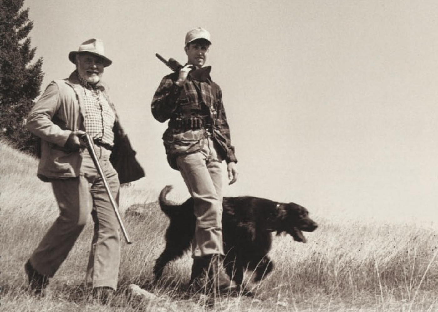 Two men outdoors in casual apparel with an Irish Setter dog in tall grass, vintage style