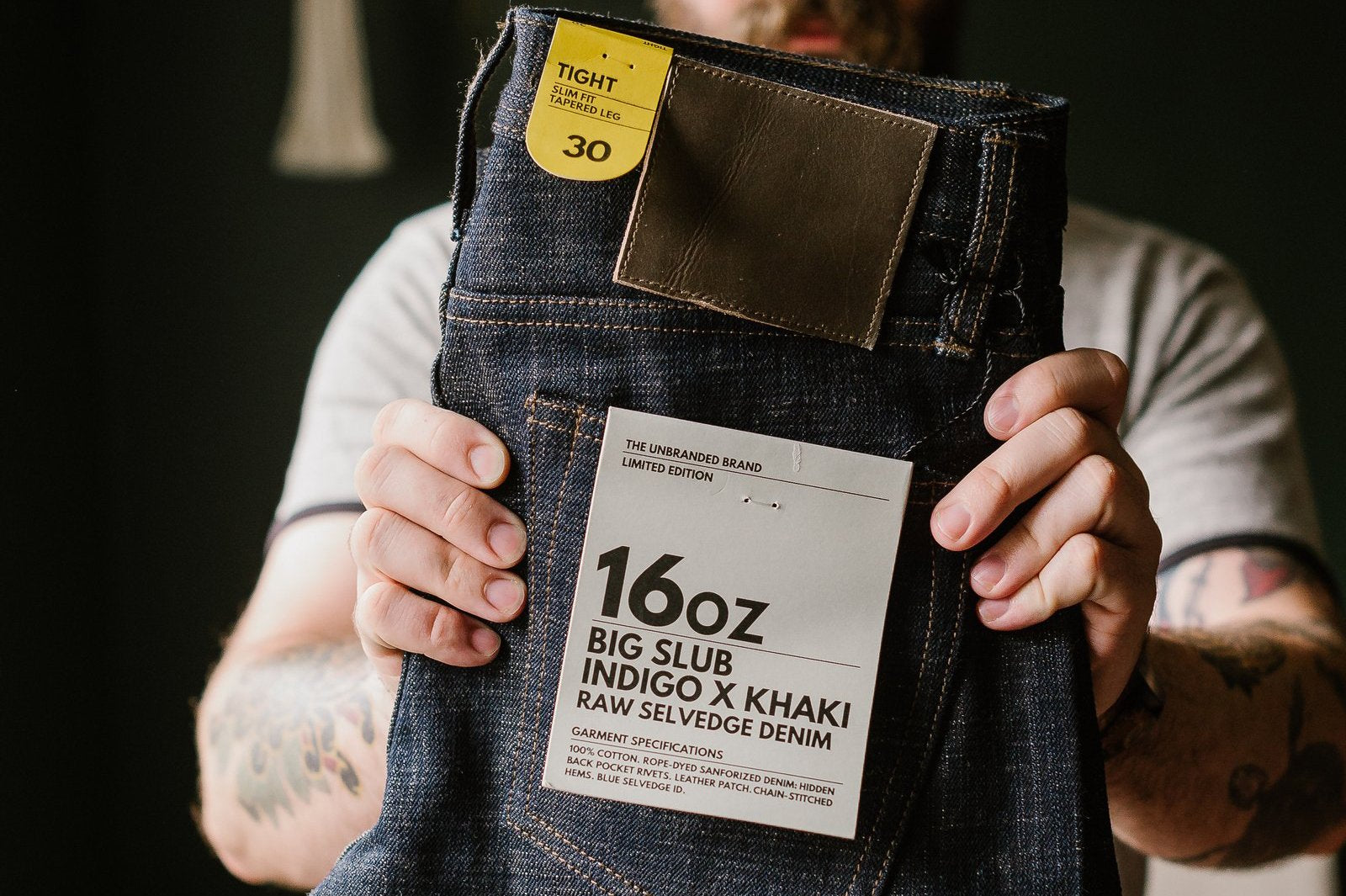 Person holding 16oz big slub indigo khaki raw selvedge denim jeans by Dant, close-up