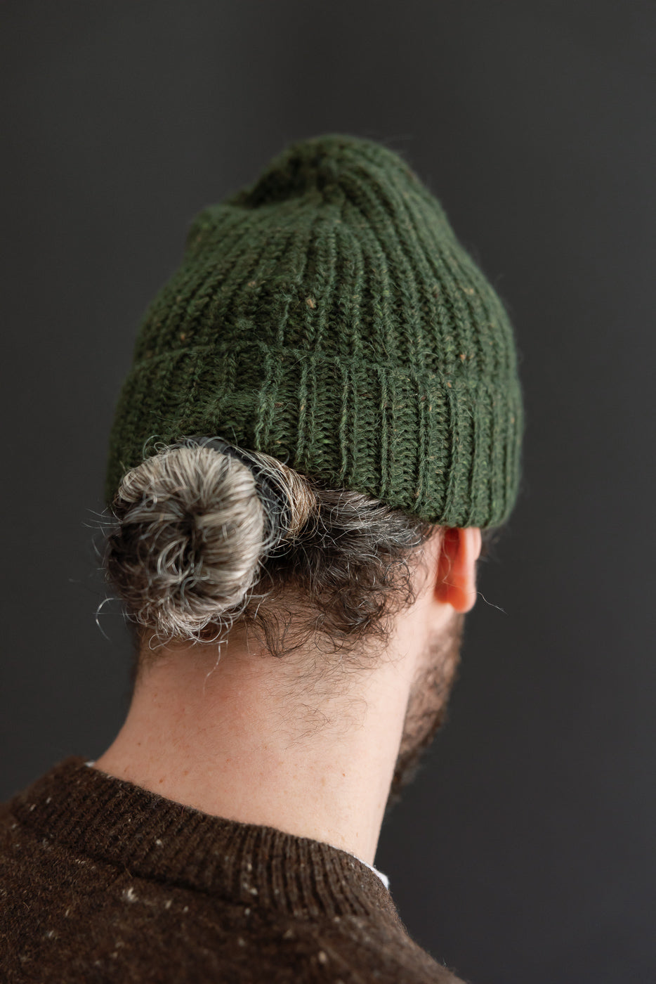 Close-up back view of a green ribbed knit beanie on a male model, 5'9