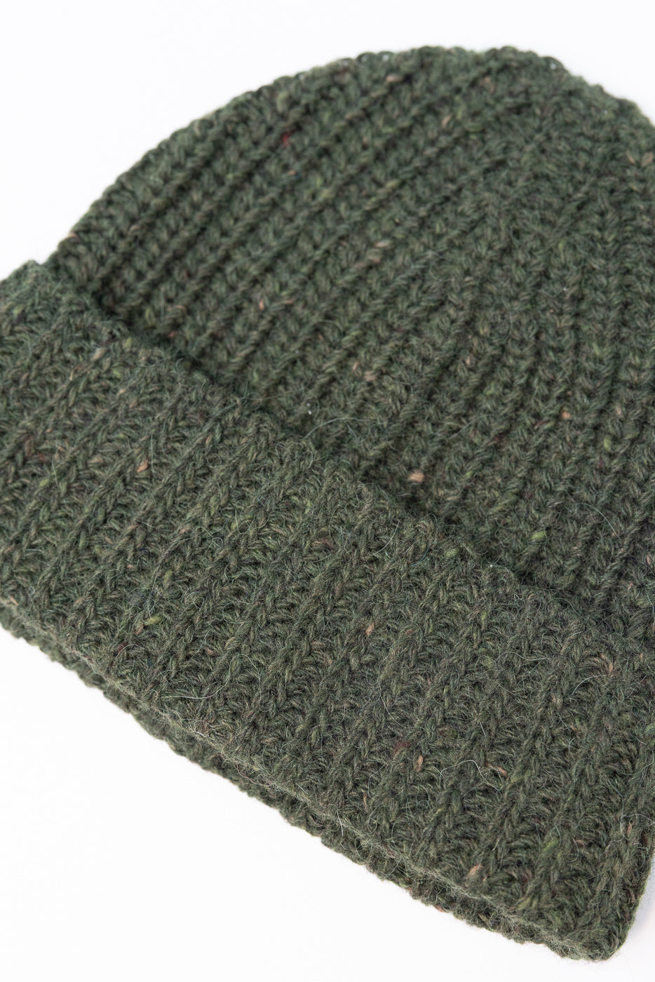 Close-up of the chunky ribbed knit texture on a dark green beanie.