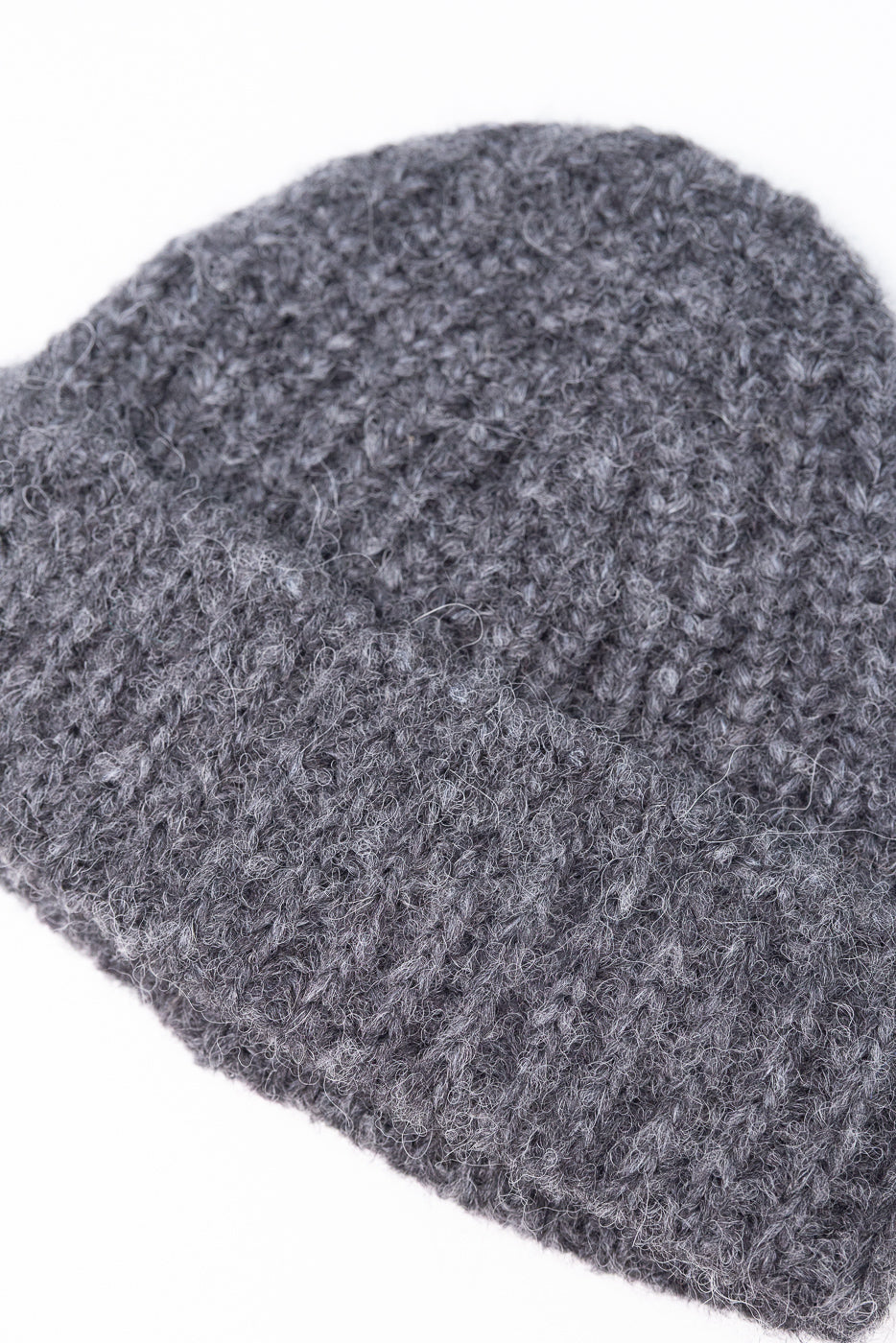 Close-up of the front texture and knit pattern of a grey wool beanie hat.