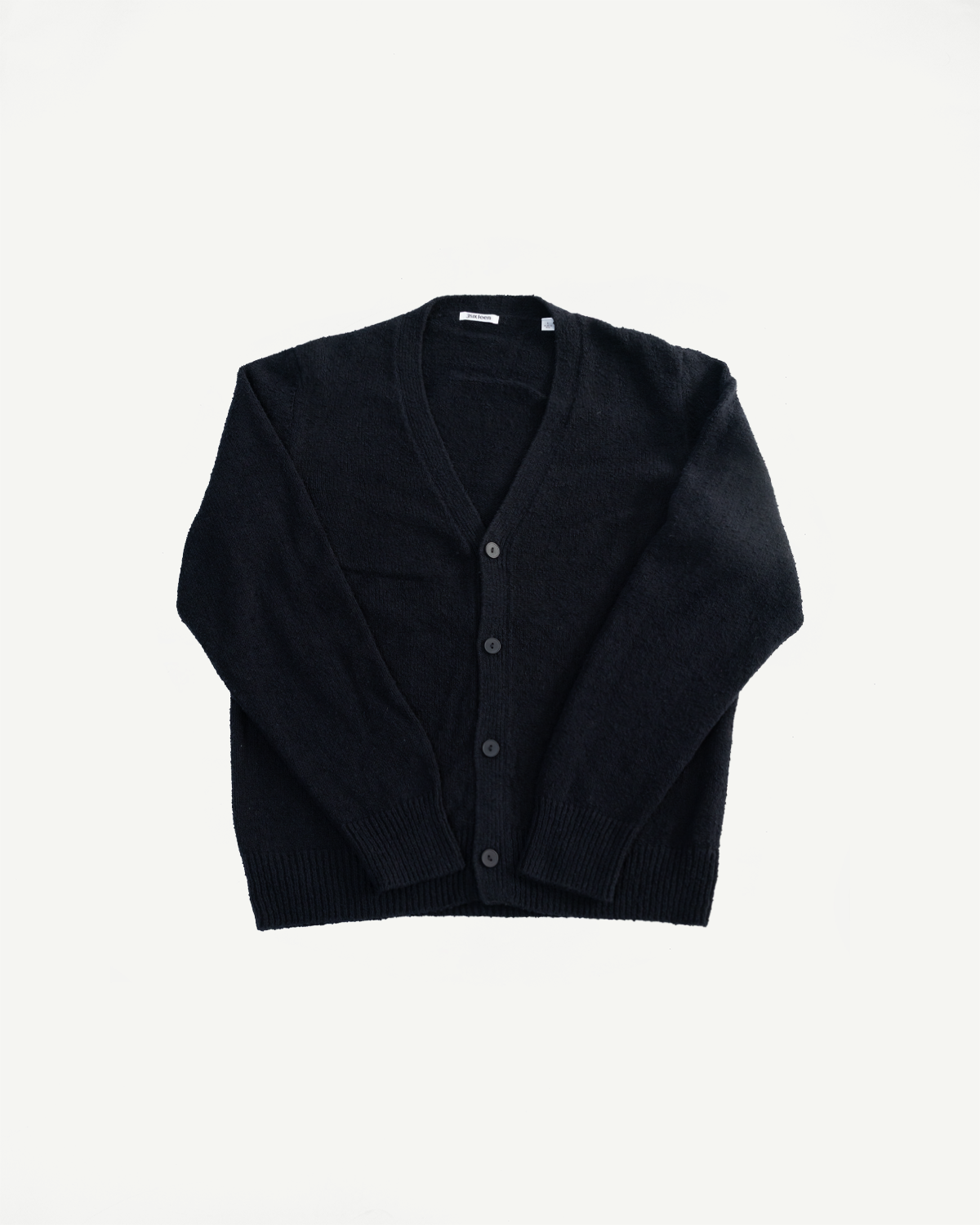 Flat lay of classic black boucle cardigan, front view, showing V-neck, buttons, ribbed cuffs and hem.
