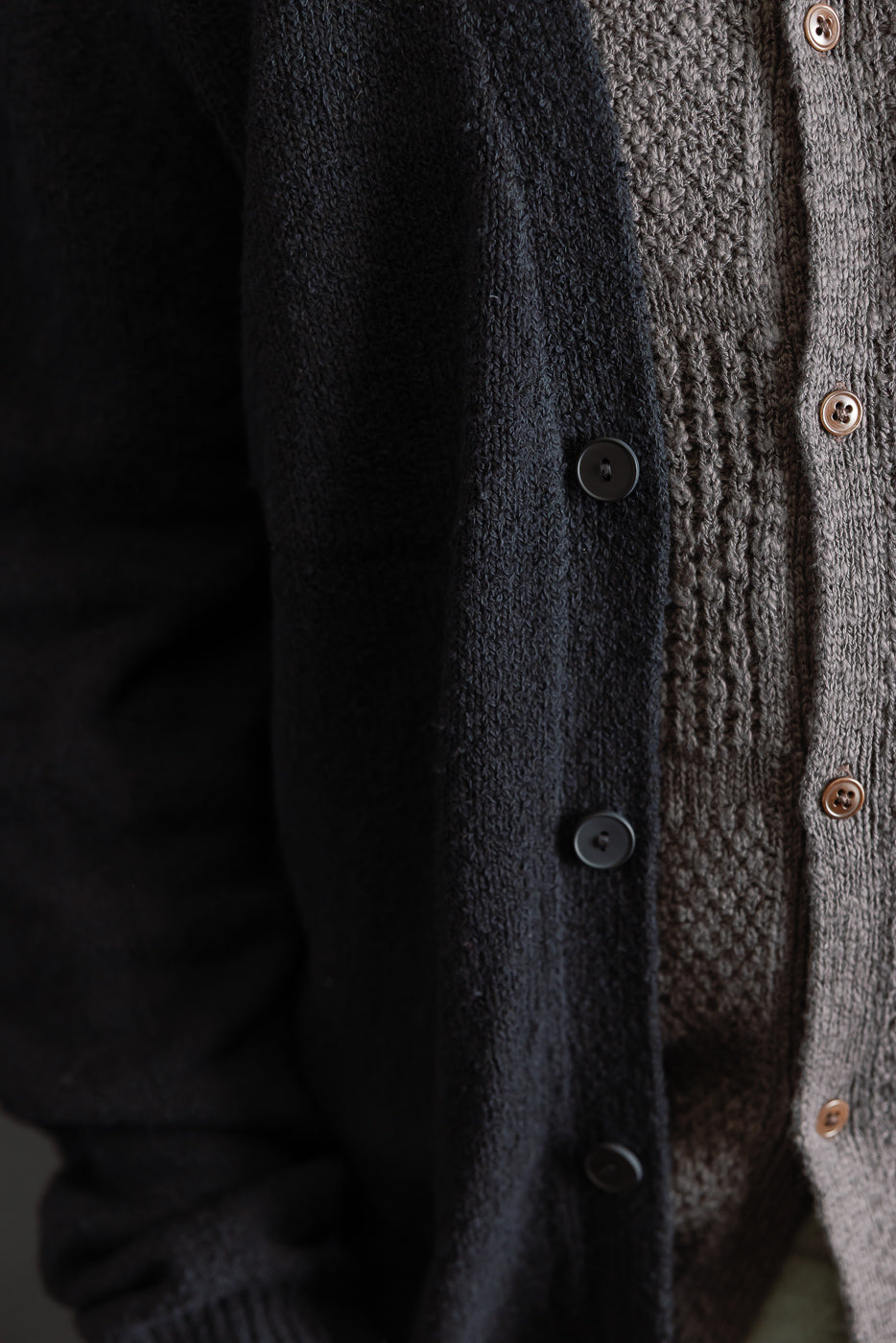 Close-up of male model wearing black boucle cardigan, front torso view, button detail visible.